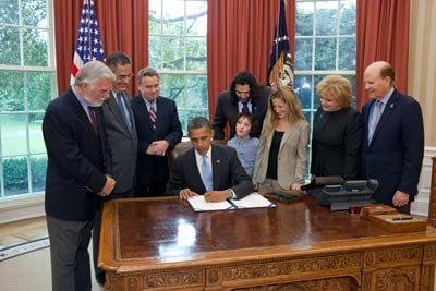 George Jesien (AUCD); Scott Badesch (ASA); Rep. Chris Smith (R-NJ); Jasper, Billy (Autism Speaks), and Gena Mann; and Suzanne and Bob Wright (Autism Speaks) with President Obama as the Combating Autism Reauthorization Act is signed.
