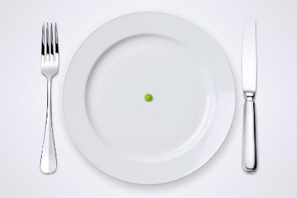 Image of a white plate with a green pea in the center with a fork and knife on each side.