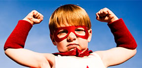 Image of a boy wearing a red cape flexing his muscles