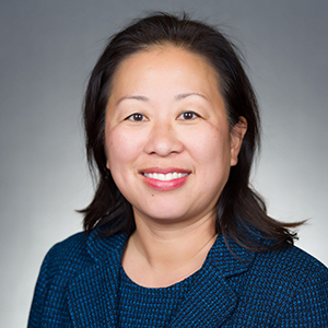 Asian american woman wearing a blue suit smiling at the camera.
