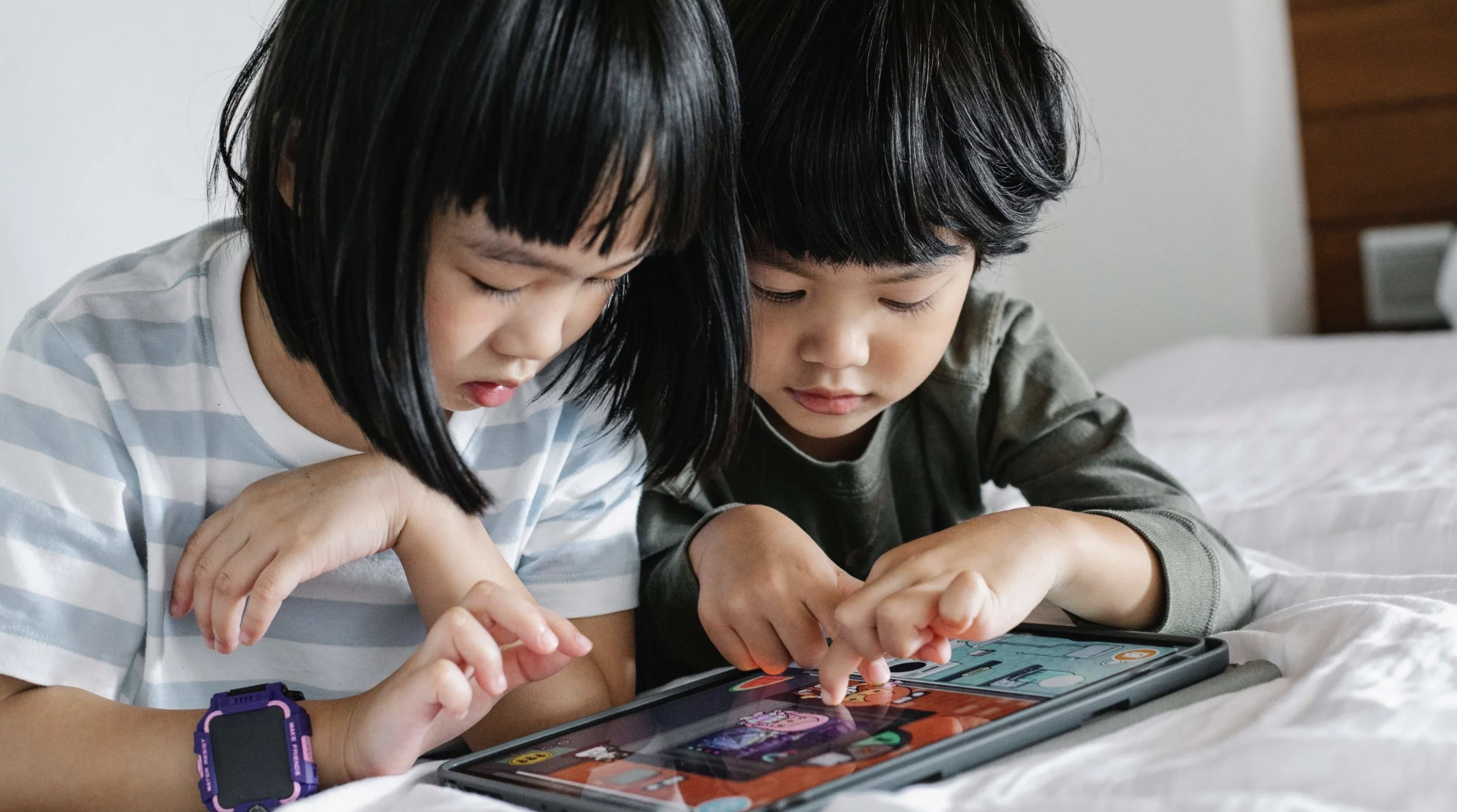 Two young children play on an iPad together.