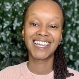 Image of Ashley Jacinth Ogbonna-Salmon, a smiling black woman with braids, she is wearing a pink shirt.