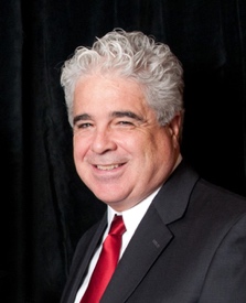 Image of Dan Crimmins, white man with grey hair wearing a suit with a red tie