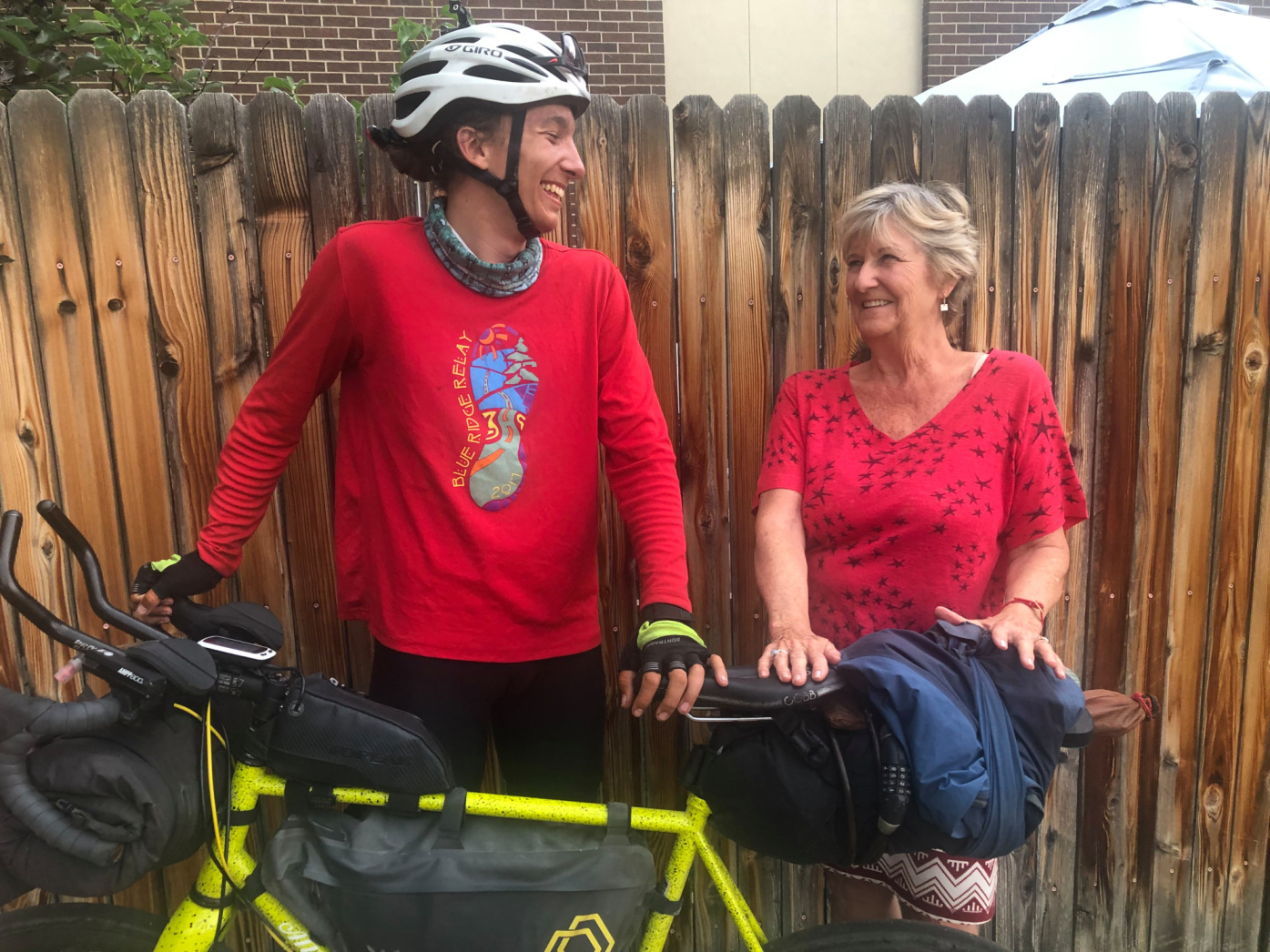 women smiling at a man with a helmet in standing next to a bike