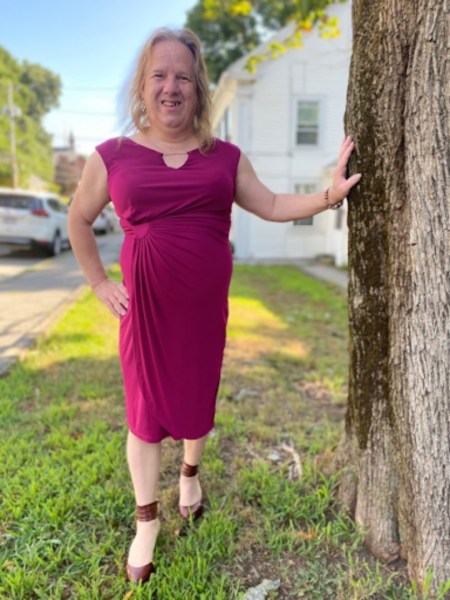 Woman in purple dress posing by a tree