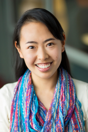 Image of a young Asian woman with her hair worn back wearing a blouse and colorful scarf smiling at the camera.