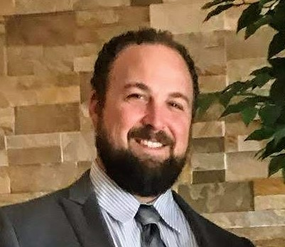 man with beard smiling at the camera and wearing a tie and jacket