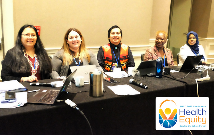 Photo of a group of presenters sitting at a conference table smiling at the camera.