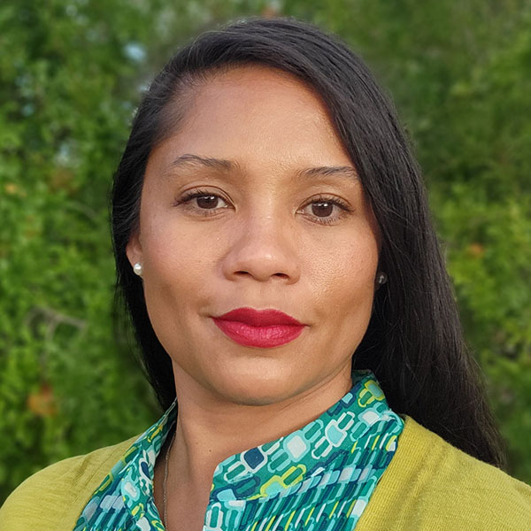 A Black-Filipina woman with long black hair wearing a sweater and blouse.