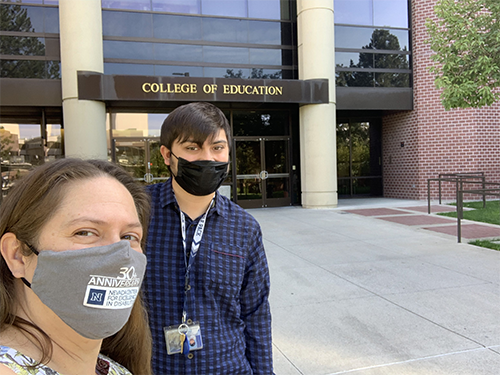  A young man and a woman wearing face masks pose for a selfie.