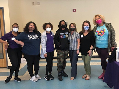 Image of 7 women standing next to each other wearing face masks.