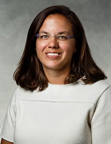 Image of a African American woman with shoulder thength hair wearing a white blouse.