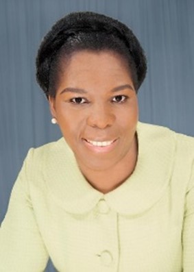 Image of a black woman with short hair and a headband wearing earing and a sweater smiling at the camera.