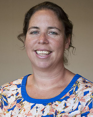 Image of a white woman with her hair pulled back wearing a floral blouse smiling at the camera.