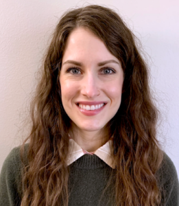 Image of a white woman with long brown hair wearing a sweater and smiling at the camera.
