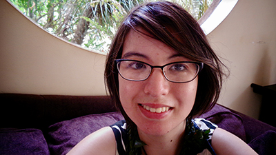 Image of a white woman with short wavy hair wearing glasses and a tank top smiling at the camera.