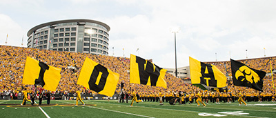 Image of cheerleading holding IOWA Banners in a filled college stadium.