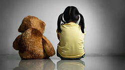 image of child sitting next a teddy bear with their back faced to the camera