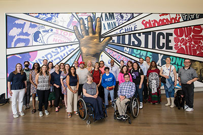 AUCD Leadership Academy participants standing/sitting in front of a mural.