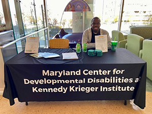 Image of a black man citting at a informationa table for the Marlaynd Center for Developmental Disabilities at
Kennedy Krieger
