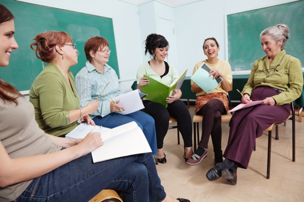 Image of six women in a semi circle conversing in a classroom