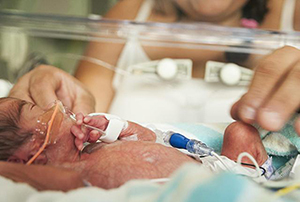 Image of a newborn in a incubator recieving care.