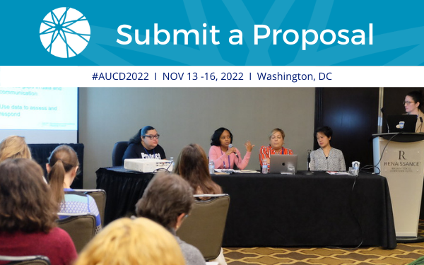 Image of 5 women sitting in front of a table presenting to group of individuals at a conference. Text Submit a Proposal! #AUCD2022 I Nov 13-16, 2022 I Washington, DC