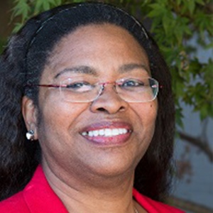Black woman wearing glasses and red jacket smiling at the camera