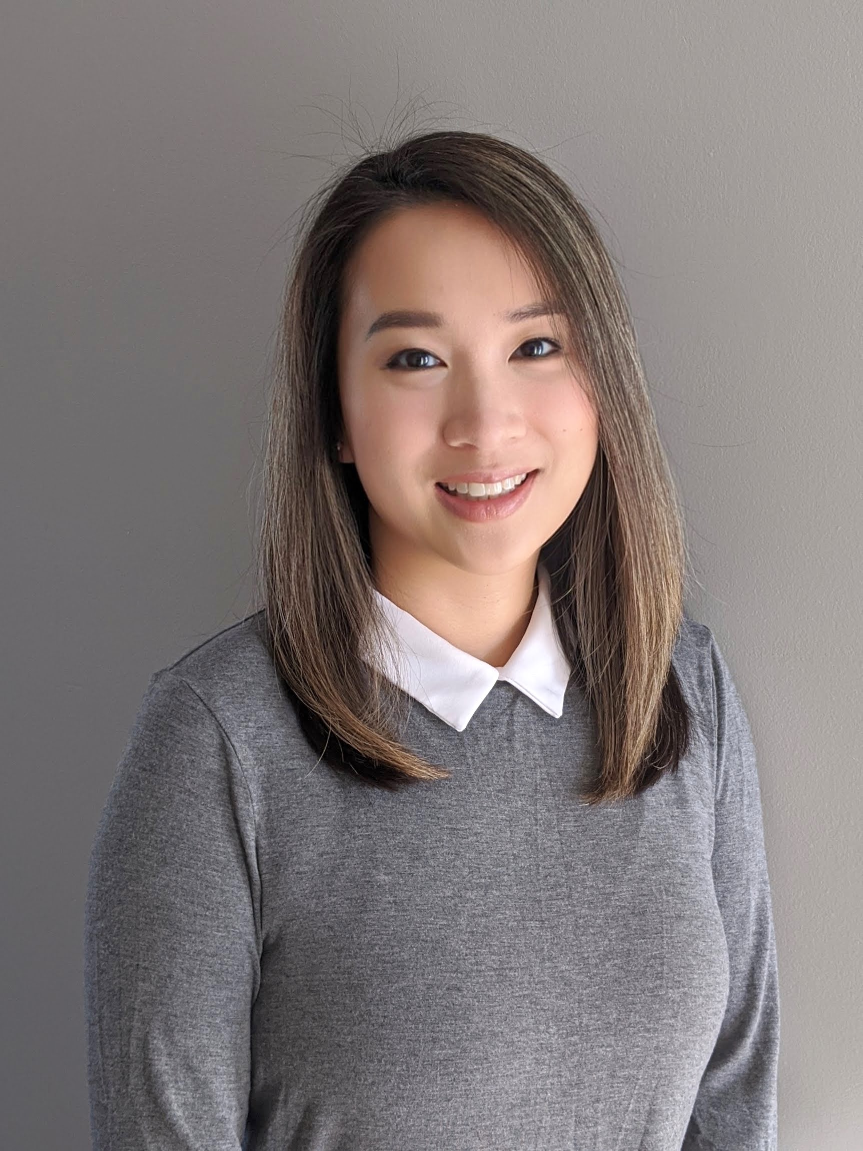 Photo of Dr. Jenny Phan, smiling woman with dark hair wearing gray and white collar against a dark gray background