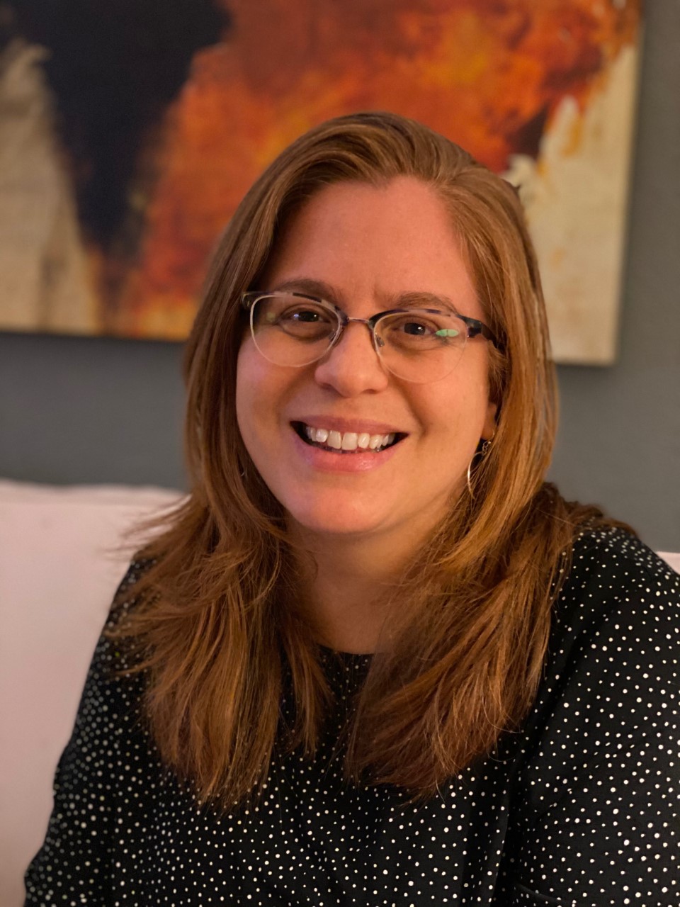 Photo of Sarah Dufek, a smiling white woman wearing glasses and a black and white polka dot shirt