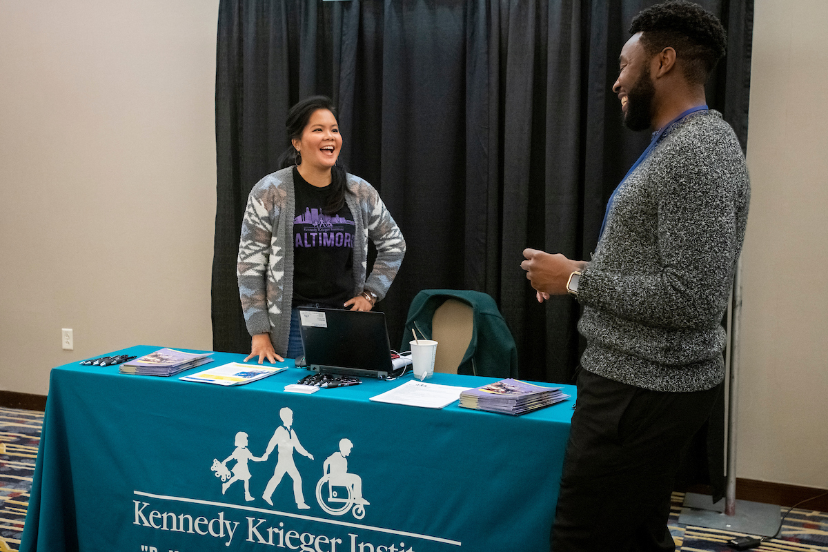 Image of Taryn Williams speaking into a microphone on the AUCD stage next to two other presenters.