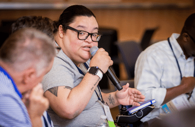 Latin woman with hair pulled back speaking into a microphone