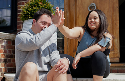 Two young individuials hig fiving eachother on the stoop.