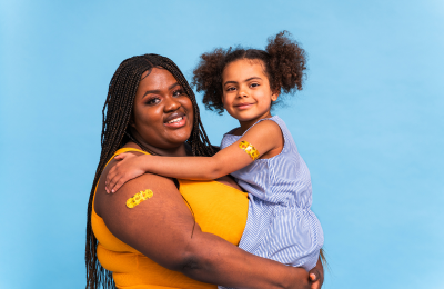 Mom is holding the child. Both have bandaids on their arms from vaccination.