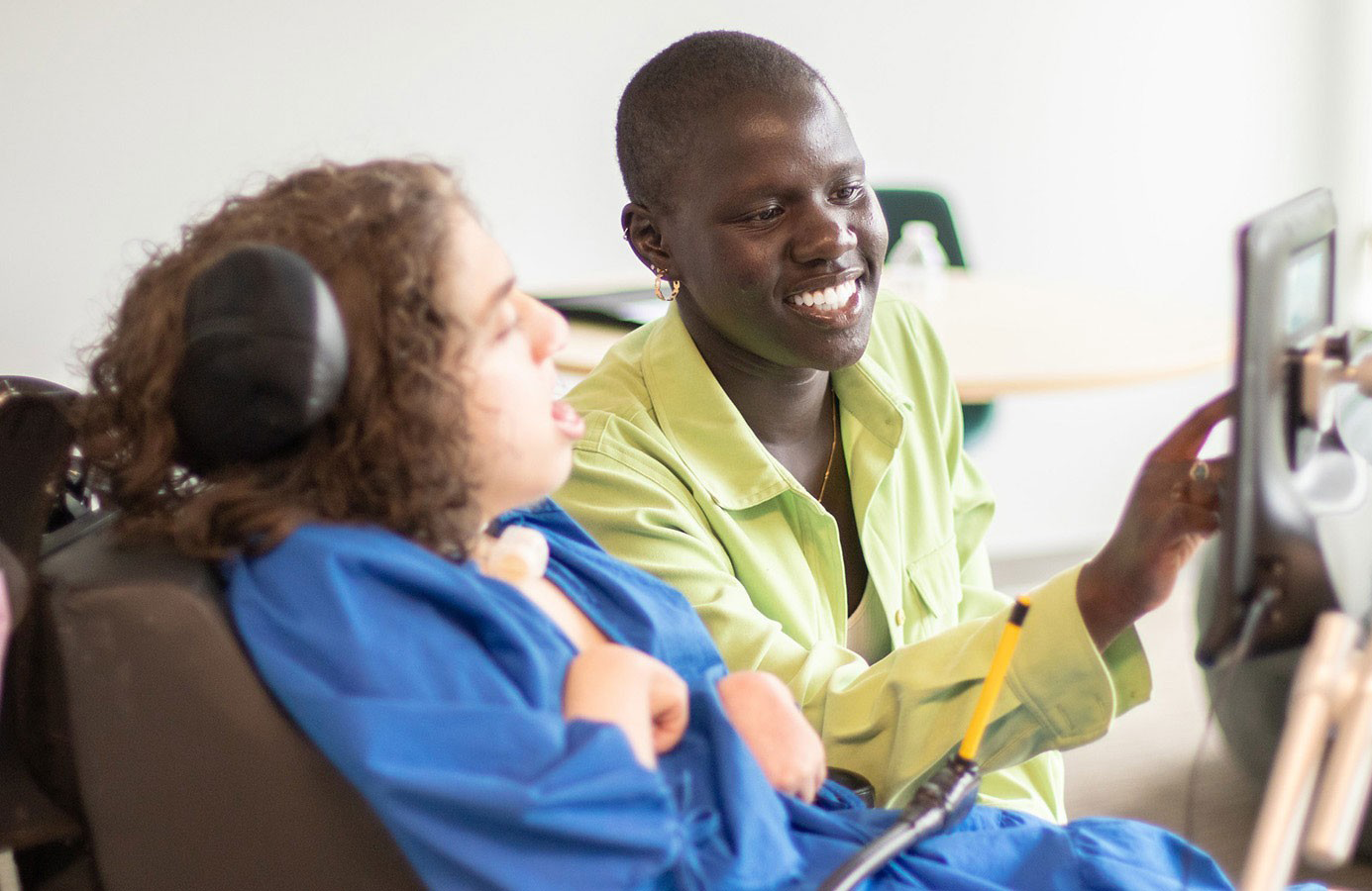 A service worker and a woman in a wheelchair look at a device together.