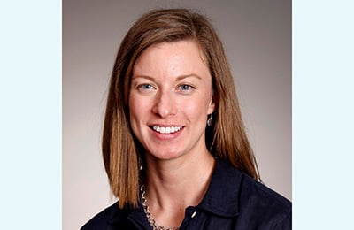 Image of a white woman with long brown hair wearing a suit and blouse.