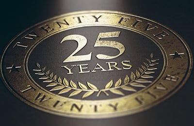 A gold emblem with "25 YEARS" embossed on the center and edges sits on a black background.