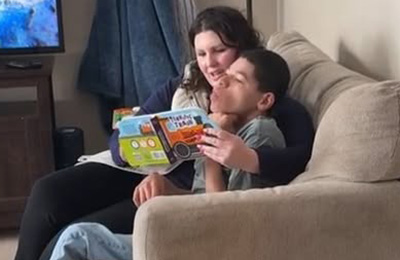  Danelle McGuire and her son Treyson Wallace sitting on a couch reading at a book together 