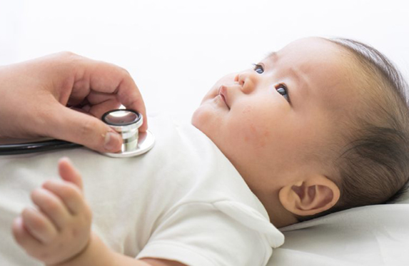 A baby in a white o A baby in a white onesie getting his heart checked by a stethoscope.nesie getting his heart checked by a stethoscope. 