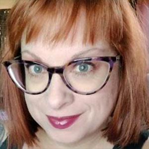 Image of Beth Boone, a smilling white woman with red hair wearing glasses.