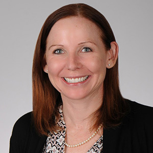 Image of Laura Carpenter, a smiling white woman with auborn hair, she is wearing a jacket and blouse.