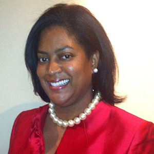 Image of Chevelle Glymph, a smiling black woman with shoulder lenght brown hair wearing a red dress, earings and a necklace. 