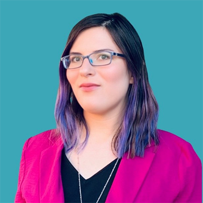 Headshot of Larissa Minner, a white woman with multicolored hair wearing glasses, a blazer, and a shirt looking at the camera. 